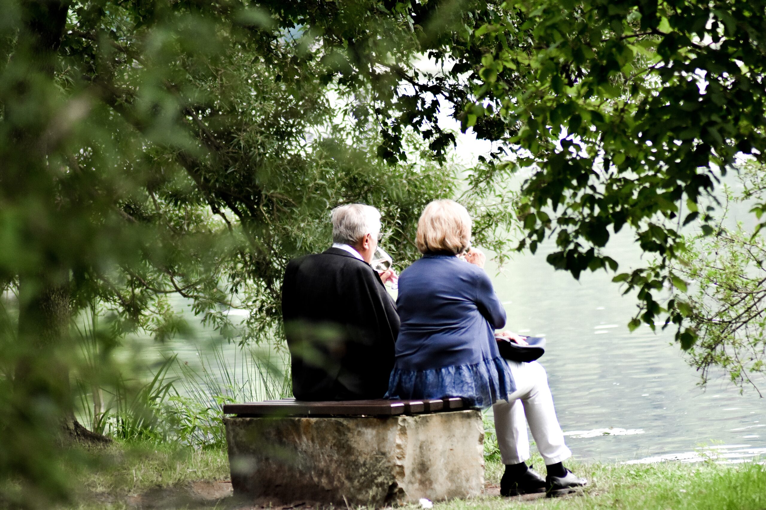 Altes Ehepaar auf einer Bank vor einem See